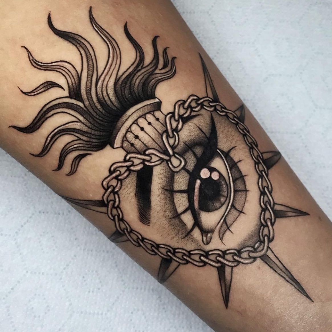 Un tatuaje de un ojo con una cadena alrededor.