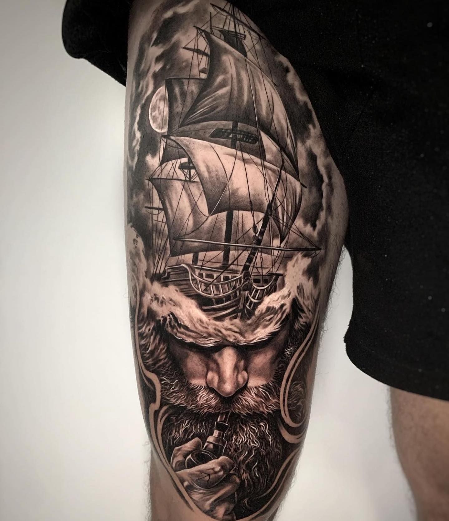 Un hombre con barba y un tatuaje de un barco en la pierna.