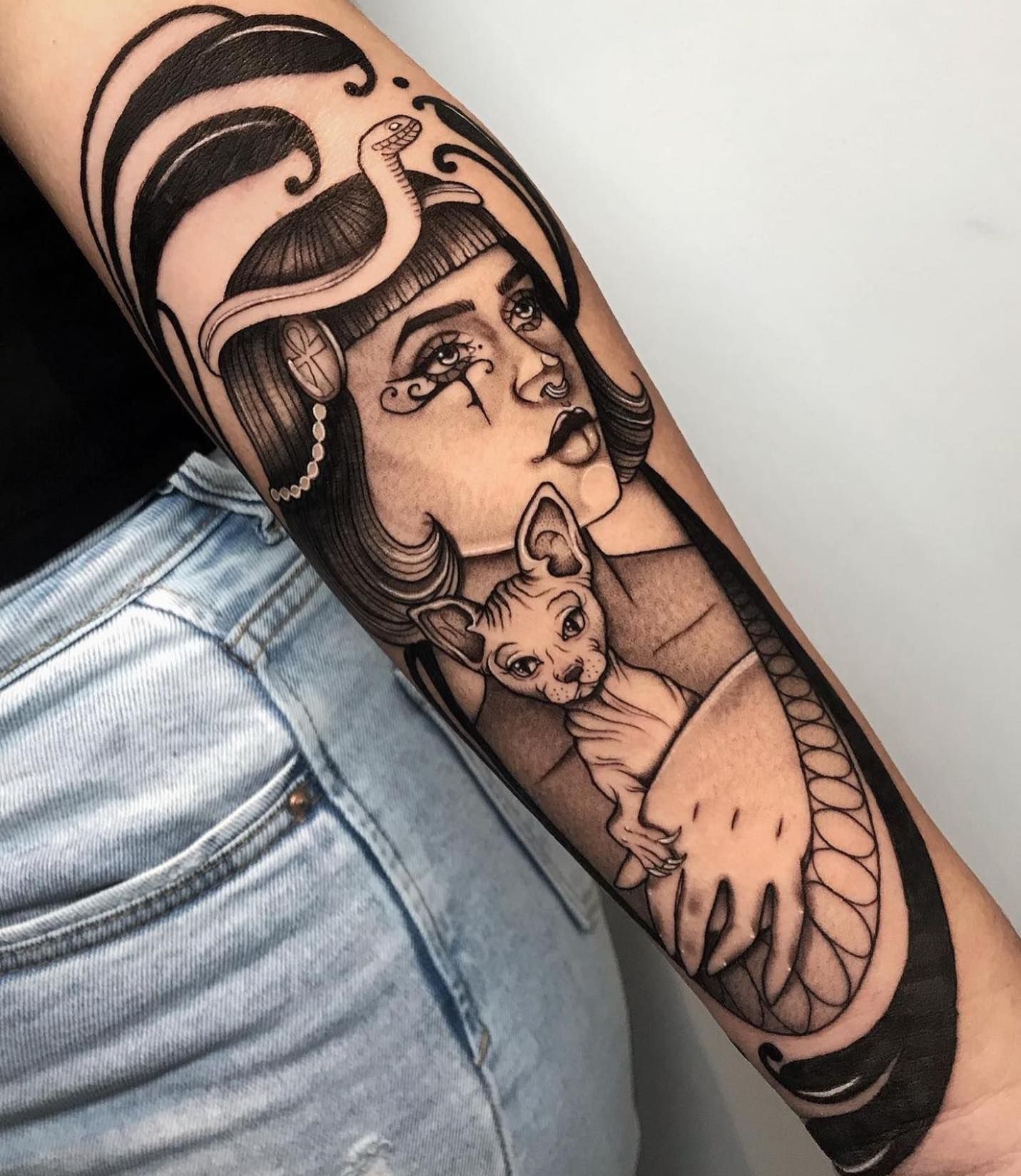 Un tatuaje de una mujer sosteniendo un gato en su brazo.