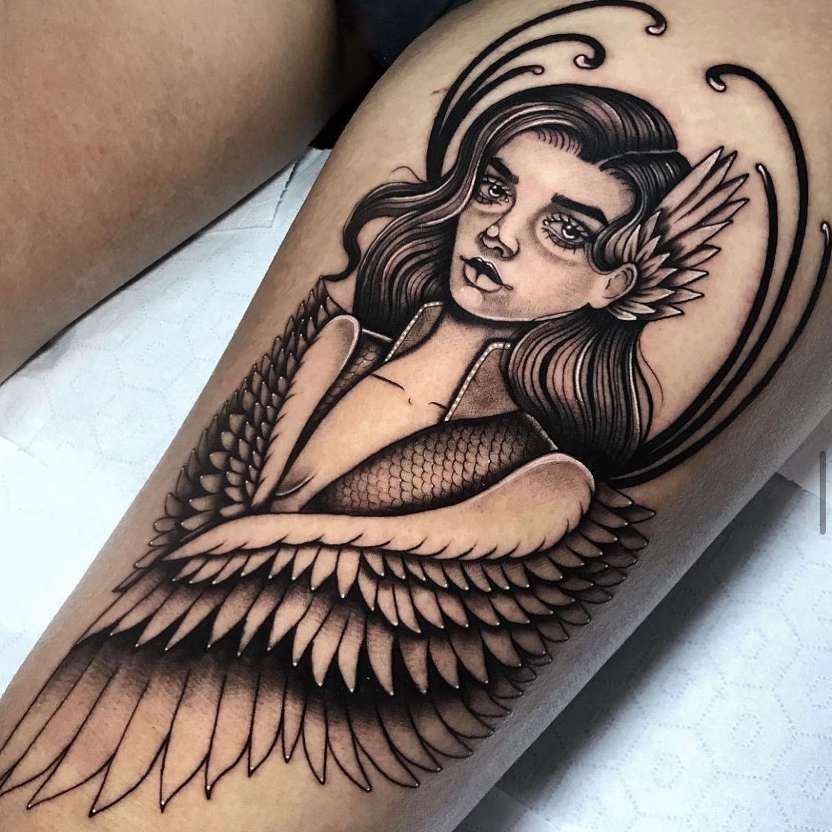 Un tatuaje de una mujer con alas en el brazo.