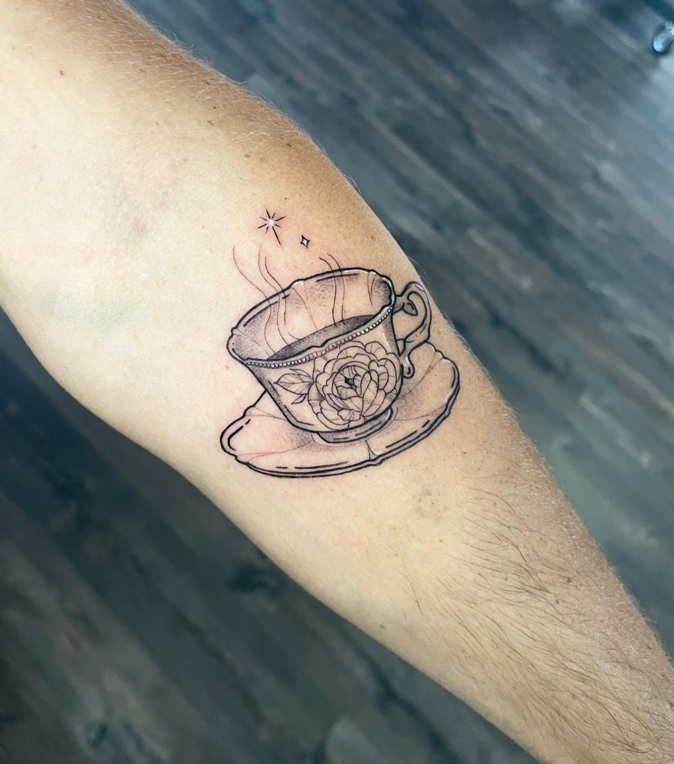Un tatuaje en blanco y negro de una taza de té en un platillo.