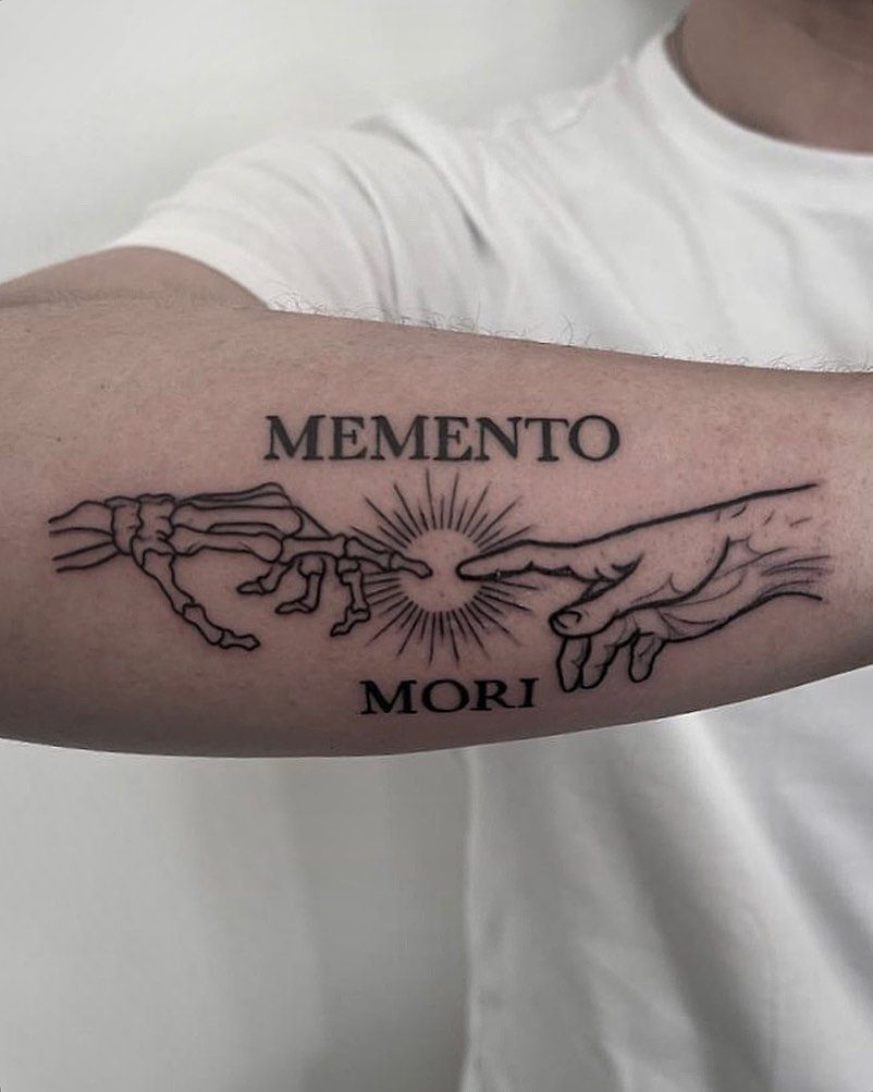 Un hombre tiene un tatuaje en el brazo que dice memento mori