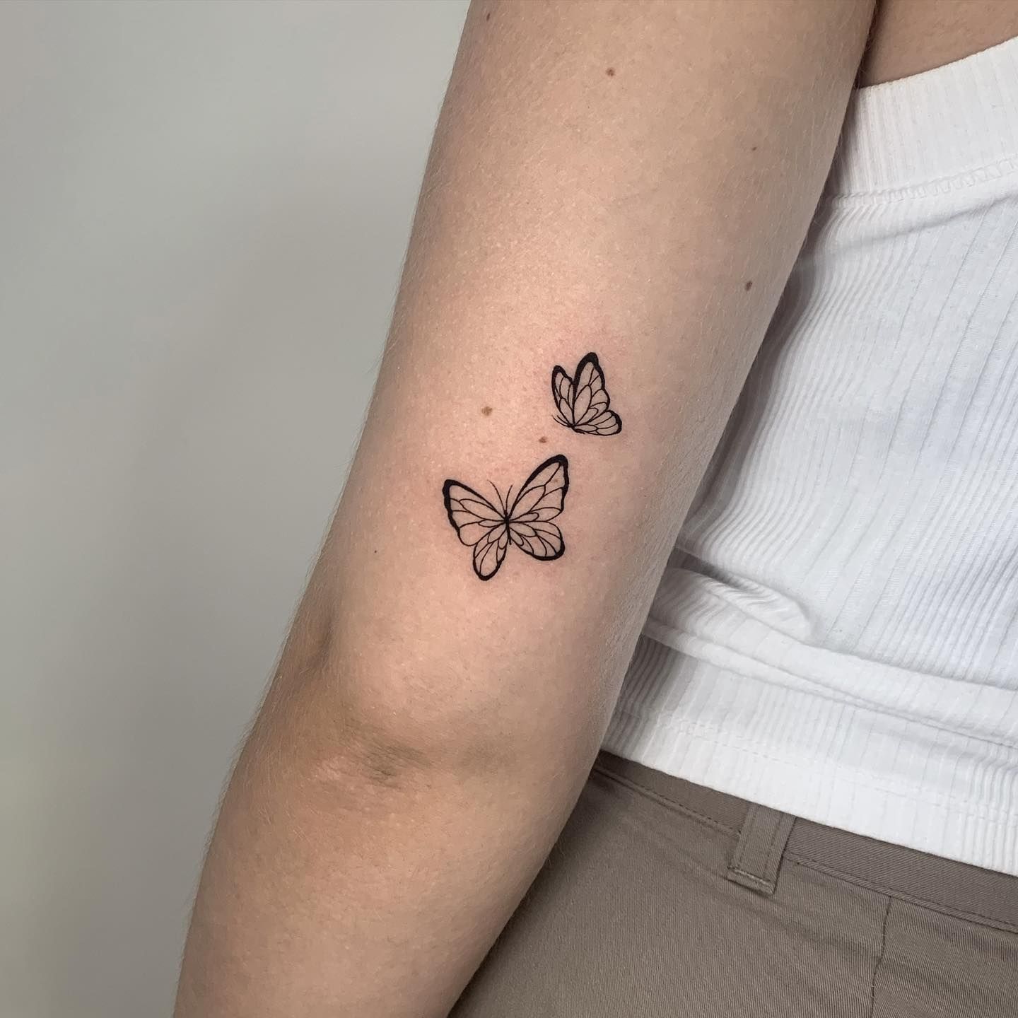 Una mujer tiene dos mariposas tatuadas en su brazo.