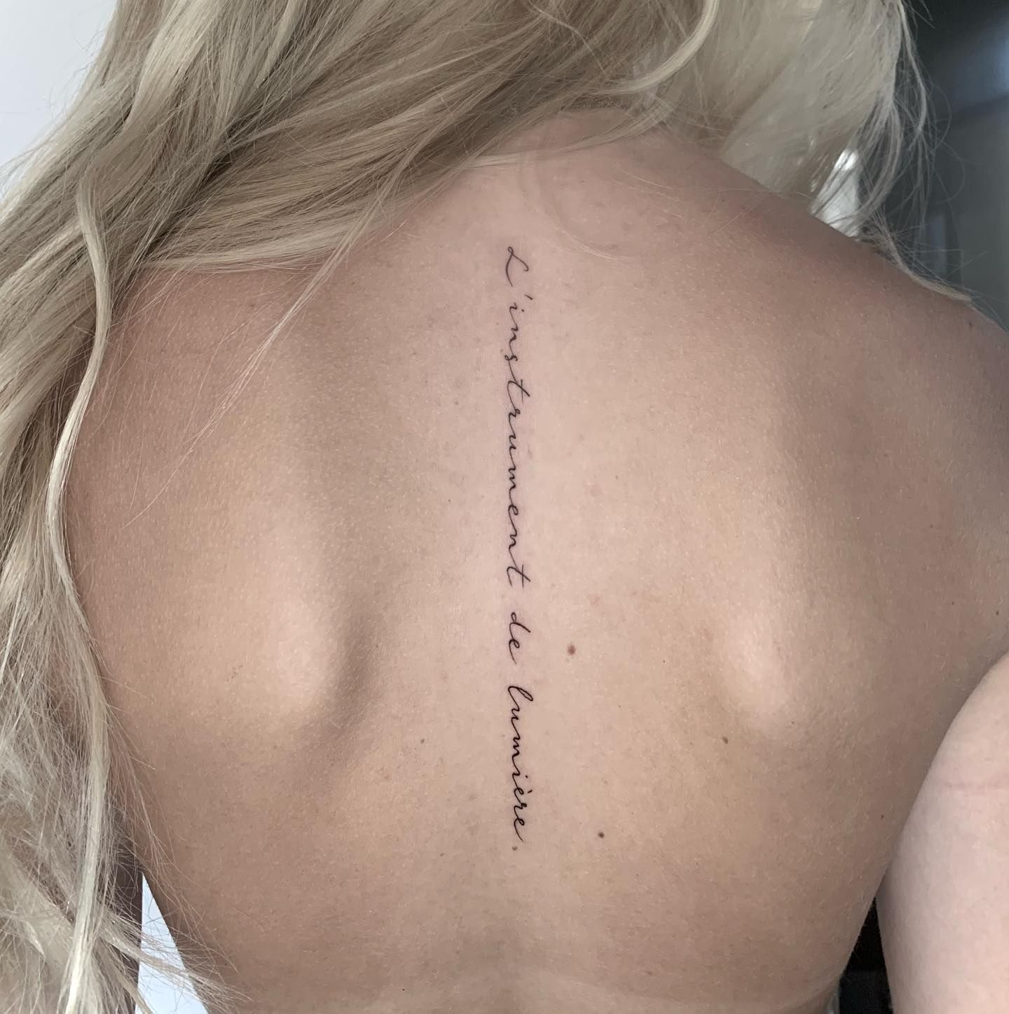 Una mujer tiene un tatuaje en la espalda que dice 