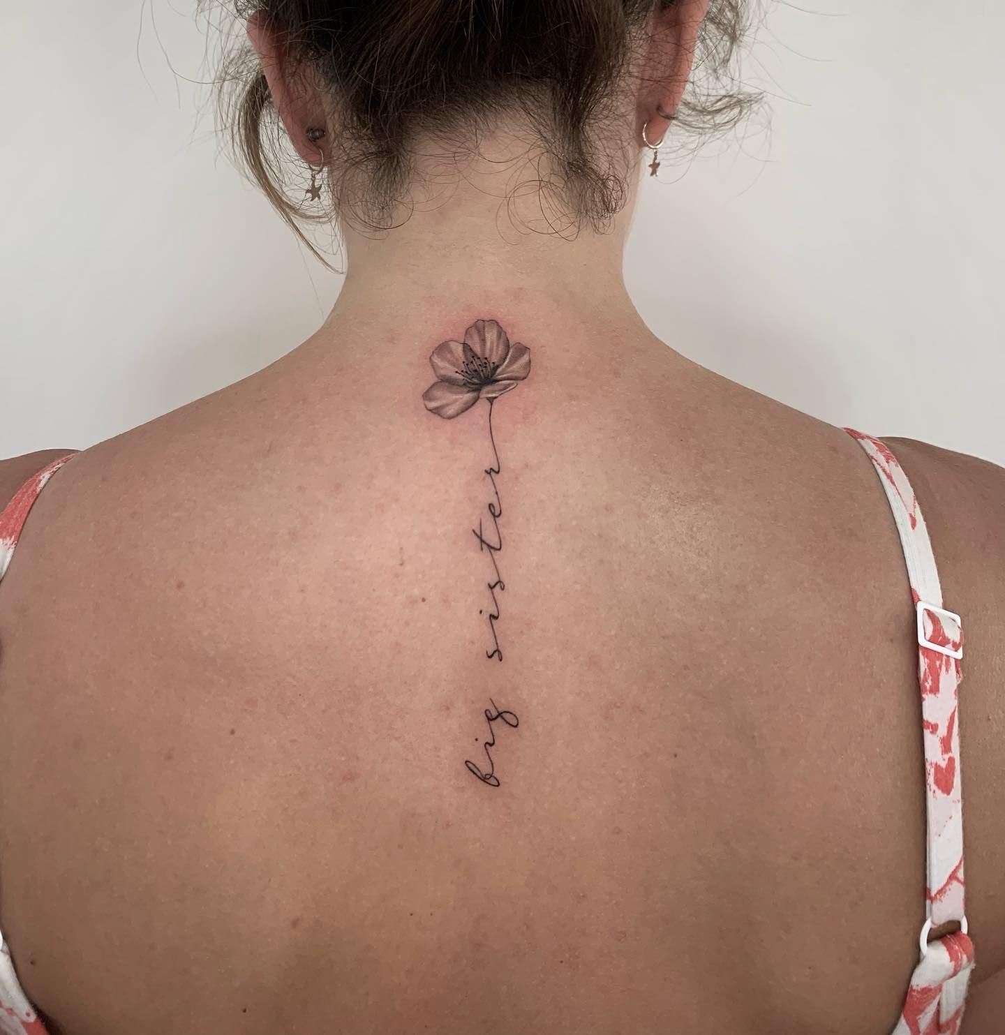 Una mujer tiene un tatuaje de una flor en la espalda.