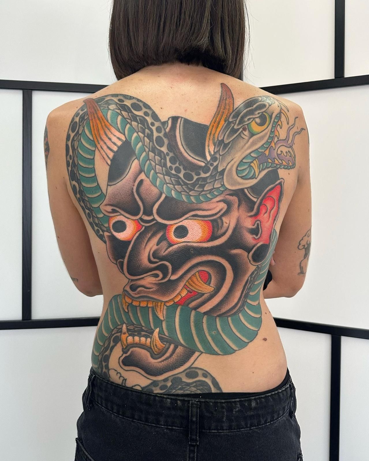 Una mujer tiene un tatuaje en la espalda de una serpiente y un demonio.