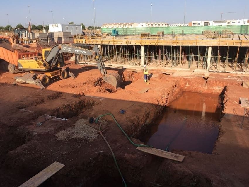 Una excavadora amarilla está cavando un hoyo en un sitio de construcción.