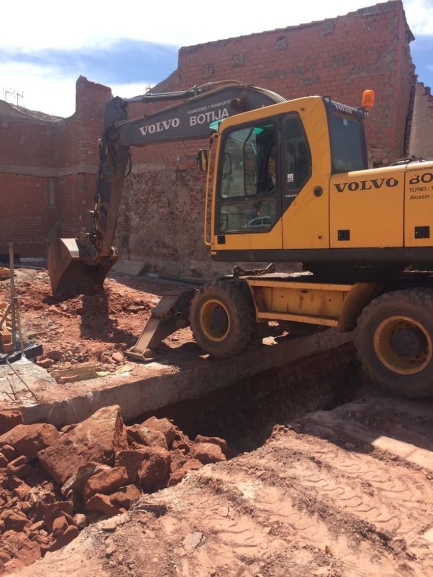 Una excavadora Volvo amarilla está cavando un hoyo en la tierra.