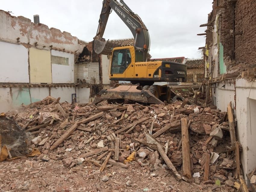 Una excavadora Volvo amarilla está demoliendo un edificio.