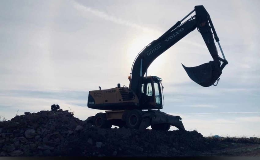 Una excavadora Volvo está encima de una pila de rocas.