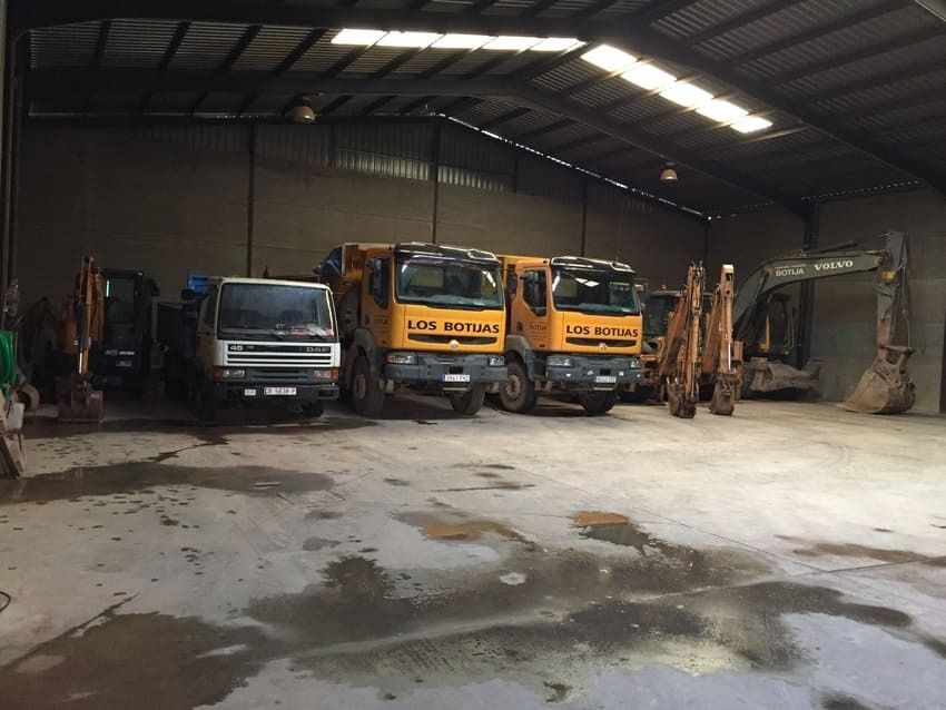 Una fila de camiones están estacionados en un almacén y uno de ellos dice les bollas