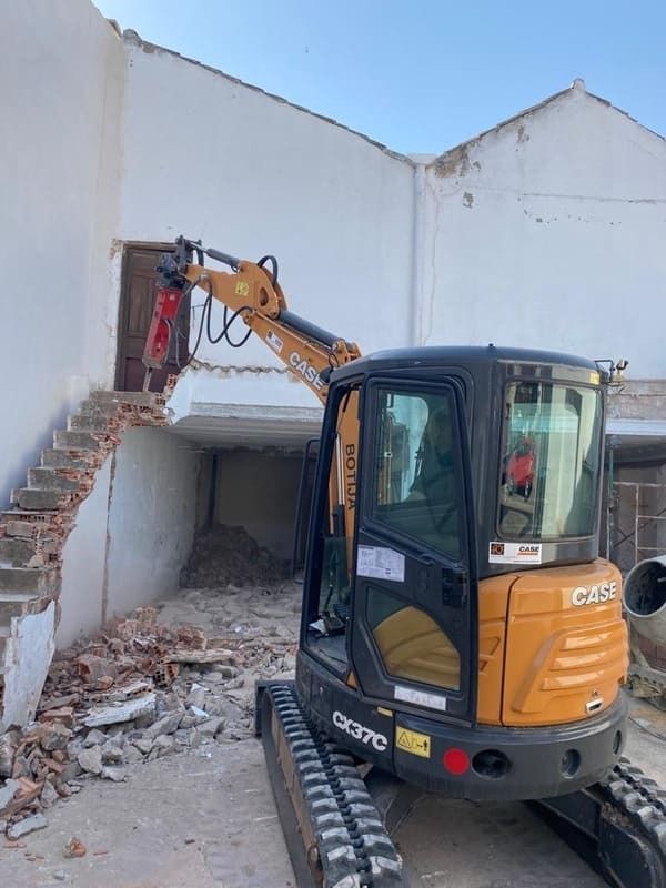 Se está utilizando una pequeña excavadora para demoler un edificio.