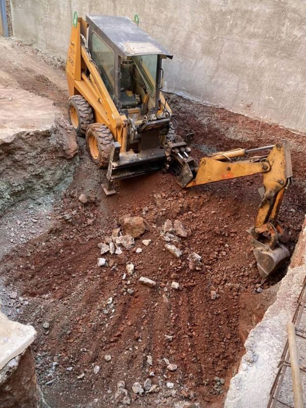 Una excavadora amarilla está cavando un hoyo en la tierra.