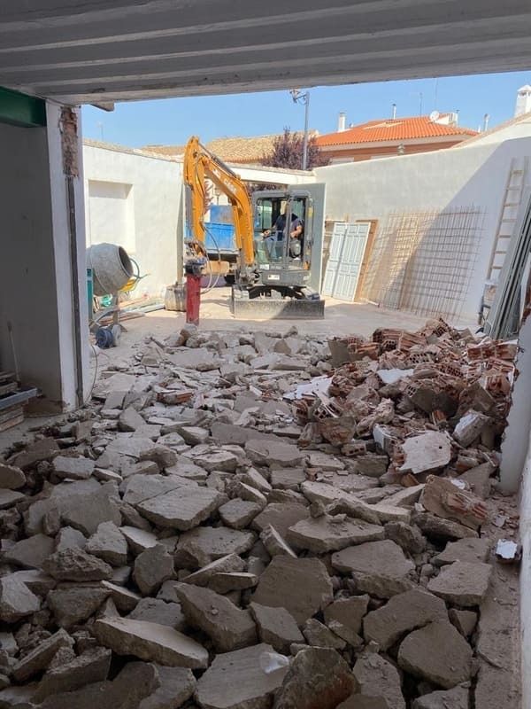 Un sitio de construcción con una excavadora amarilla al fondo