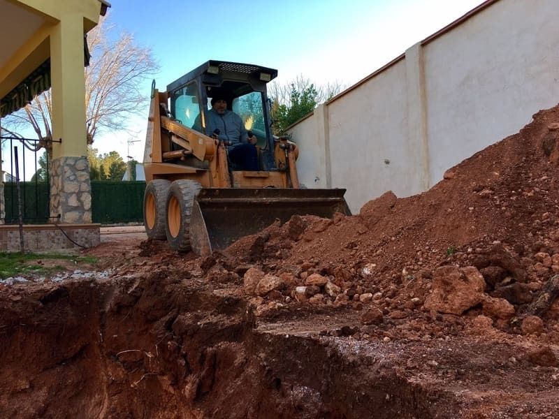 Un hombre conduce una excavadora por un camino de tierra.