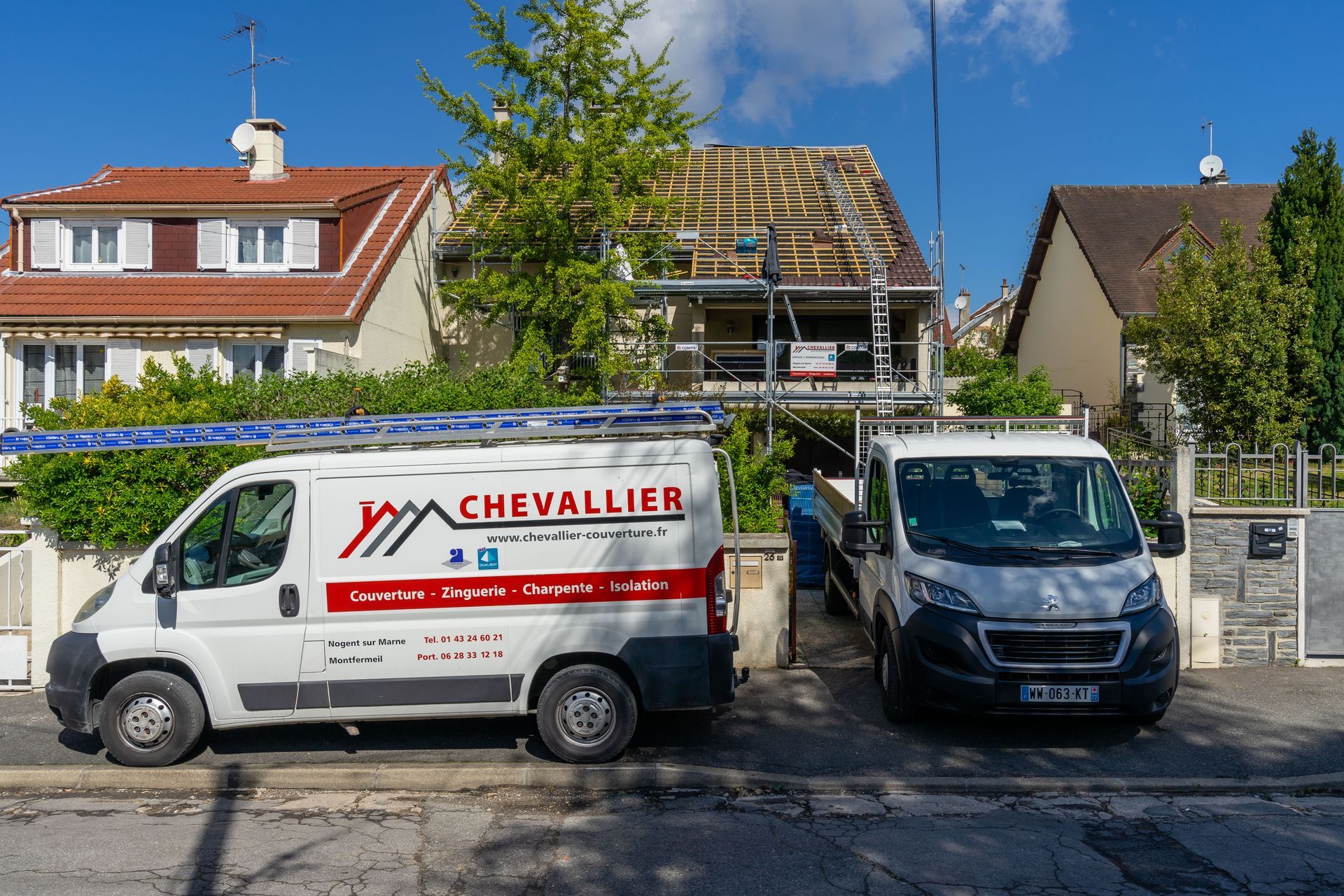 Deux camions de l'entreprise Chevallier Couverture devant une maison.