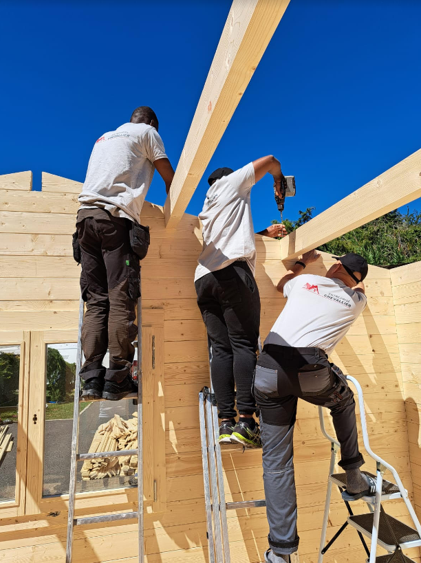 Trois couvreurs installant une charpente.