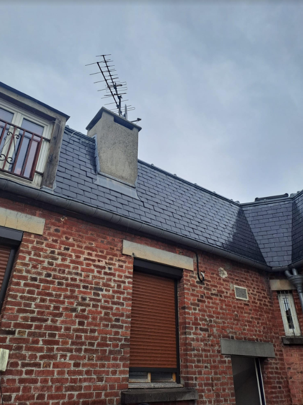 Maison ancienne en briques et toiture foncée.