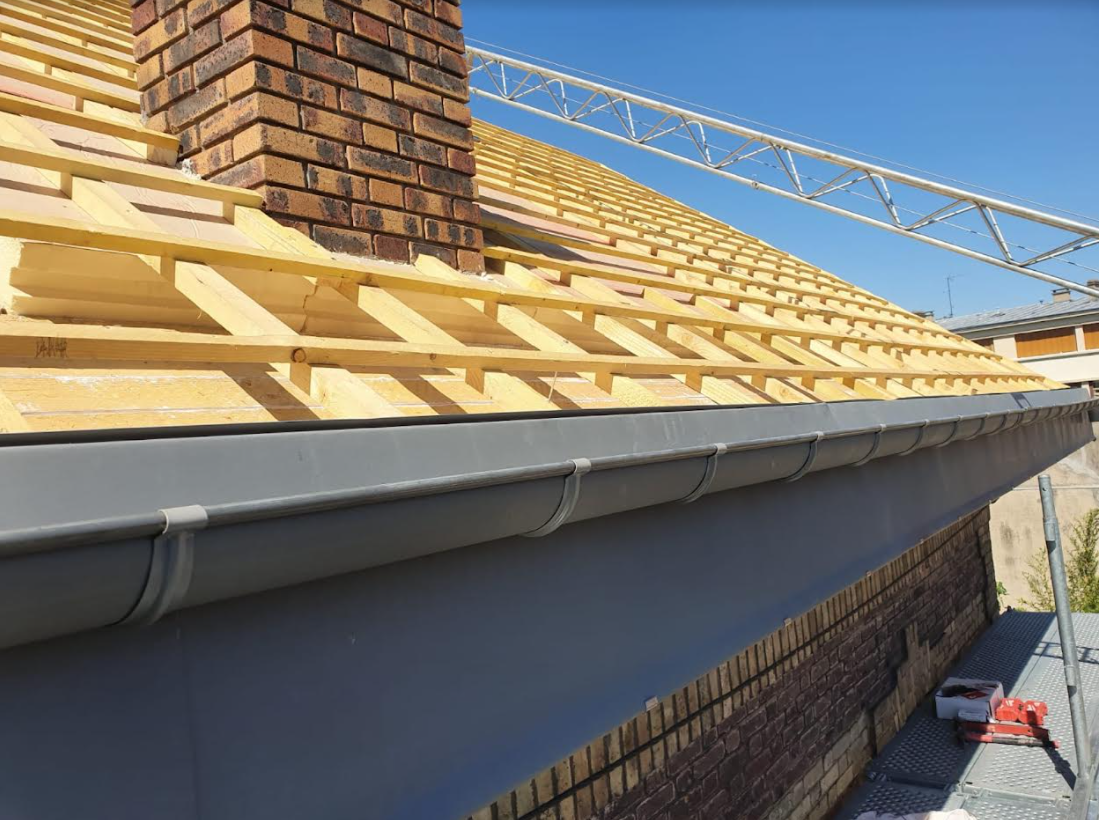 Gros plan sur une gouttière et une toiture en rénovation.