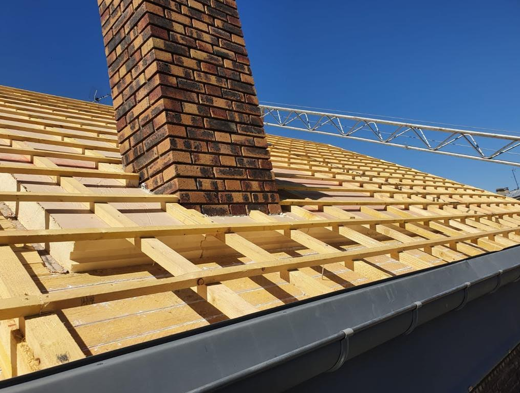 Charpente rénovée avec une cheminée au milieu.