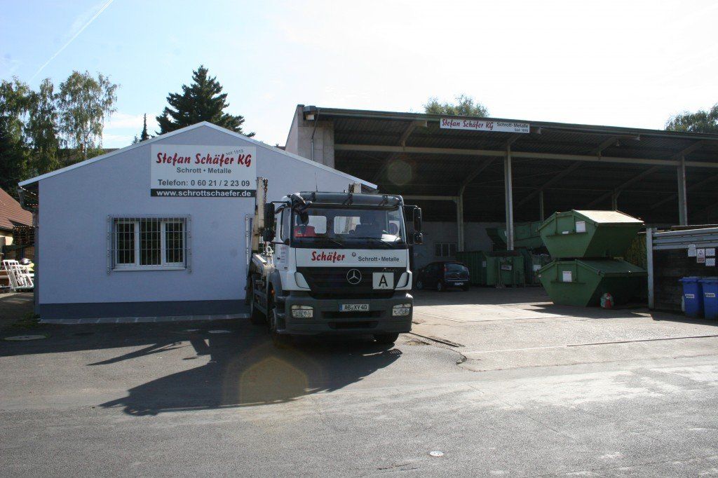 LKW vor einer Müllrecyclinganlage mit sichtbaren Gebäuden und Müllcontainern.