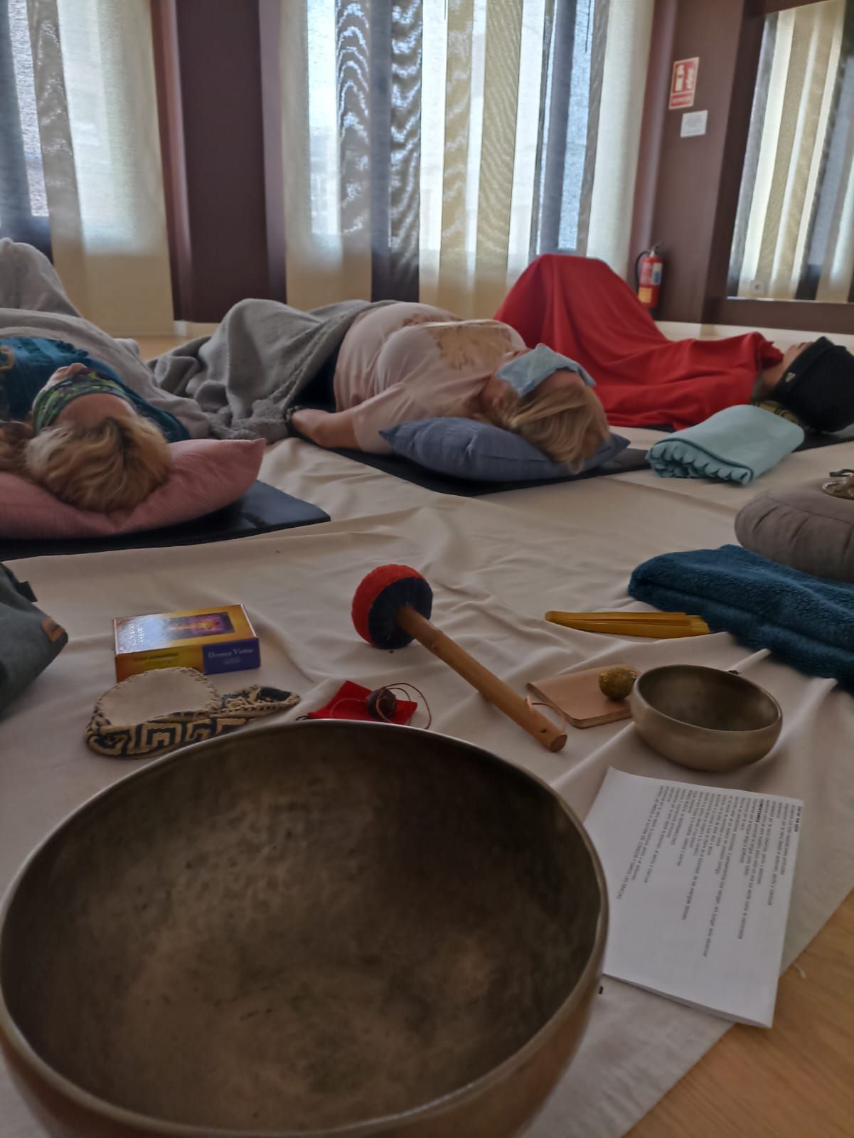 Personas tumbadas durante una sesión de baño de sonido. Instrumentos y cojines en primer plano.