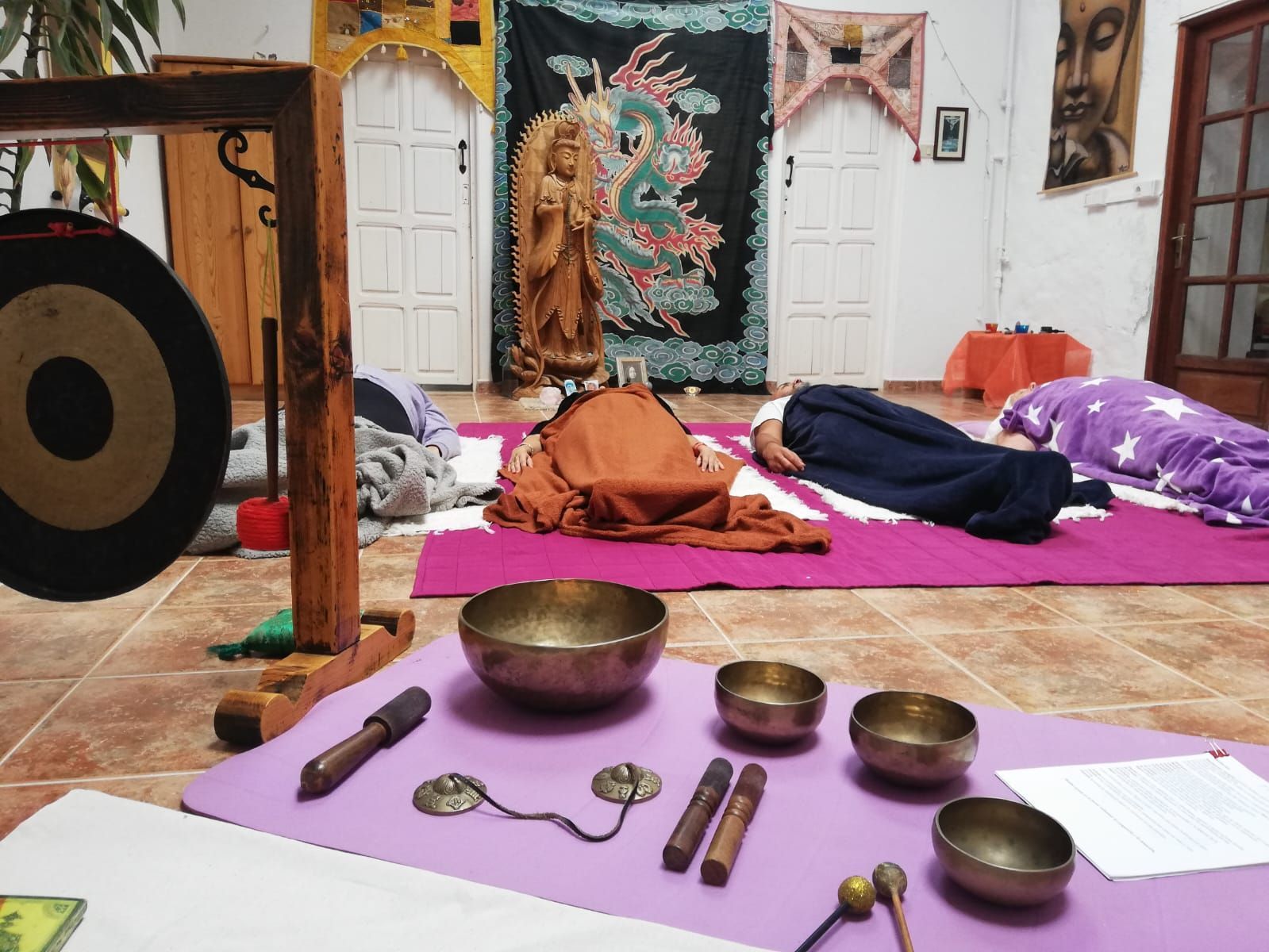 Personas en una clase de yoga, tumbadas con instrumentos delante: gongs, cuencos.
