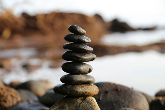 Pila de piedras lisas y oscuras equilibradas en una playa.