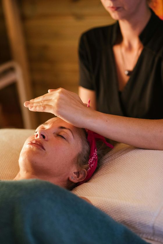 Mujer recibiendo sanación energética. El practicante sostiene las manos sobre la frente. Luz natural.