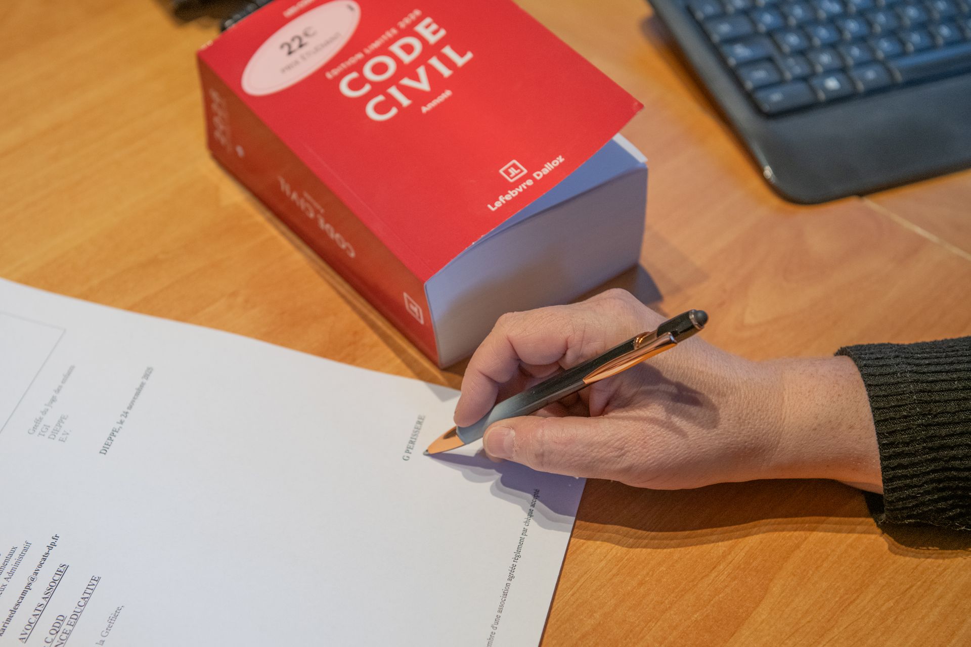 Code Civil posé à côté d'une personne signant un document