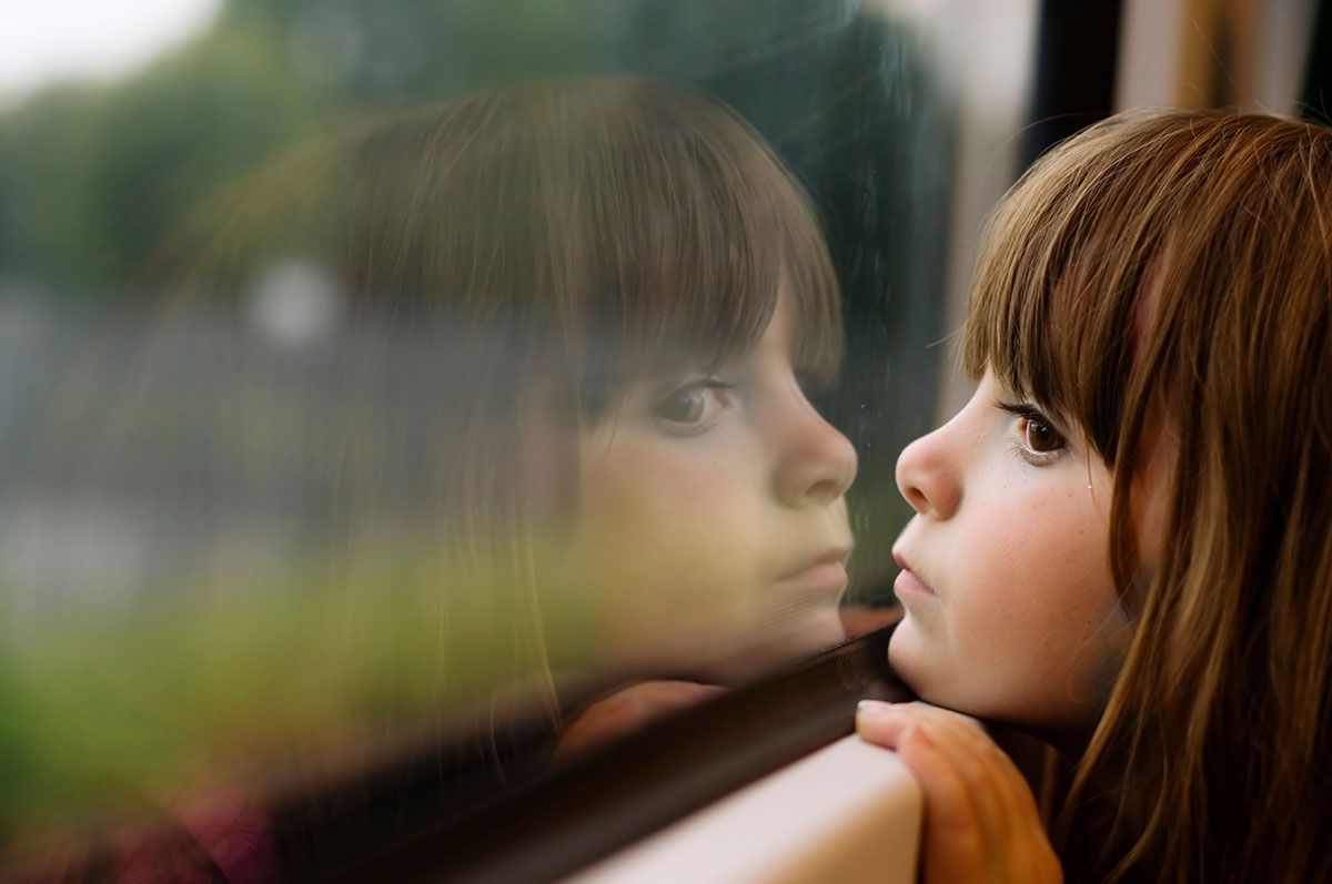 Petite fille qui se regarde dans la vitre d'un train
