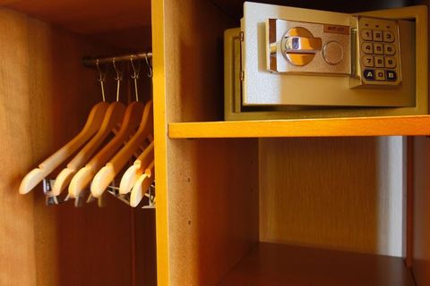 Armoire en bois avec cintres et coffre-fort numérique.