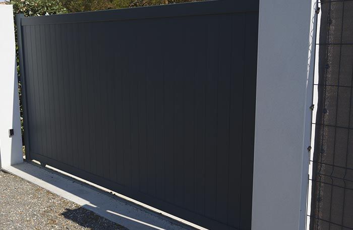 Una puerta corrediza negra está al lado de una pared blanca.