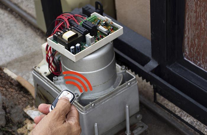 Una persona está usando un control remoto para abrir una puerta corrediza.