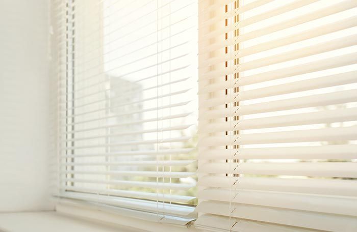 Un primer plano de una ventana con persianas blancas.
