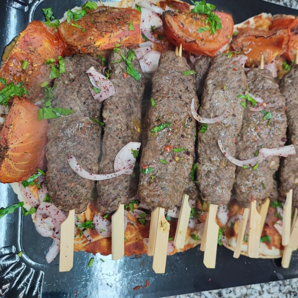 Brochettes de viande dans une assiette avec tomates cuites autour