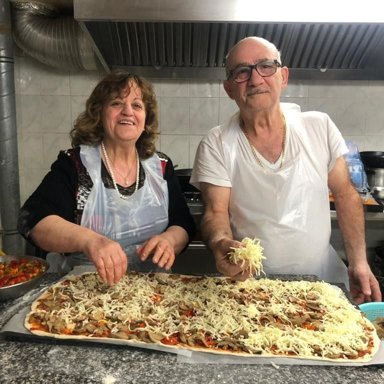 Équipe de cuisine souriante en train de préparer une pizza
