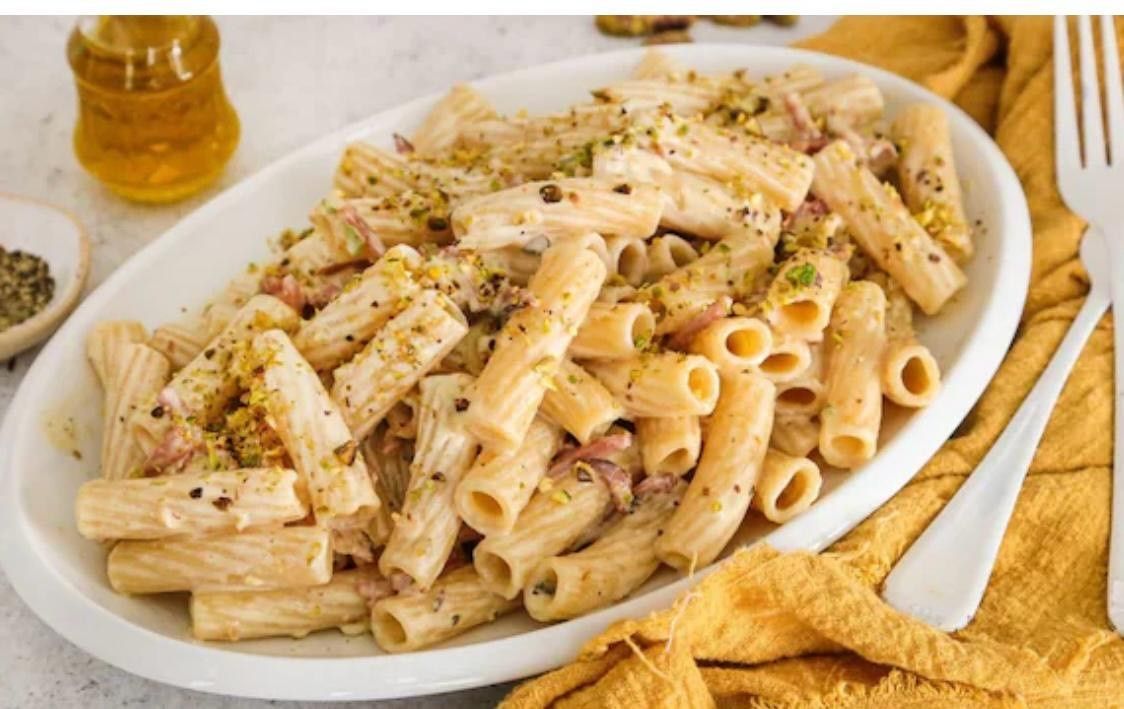 Une assiette blanche garnie de pâtes et une fourchette sur une table.