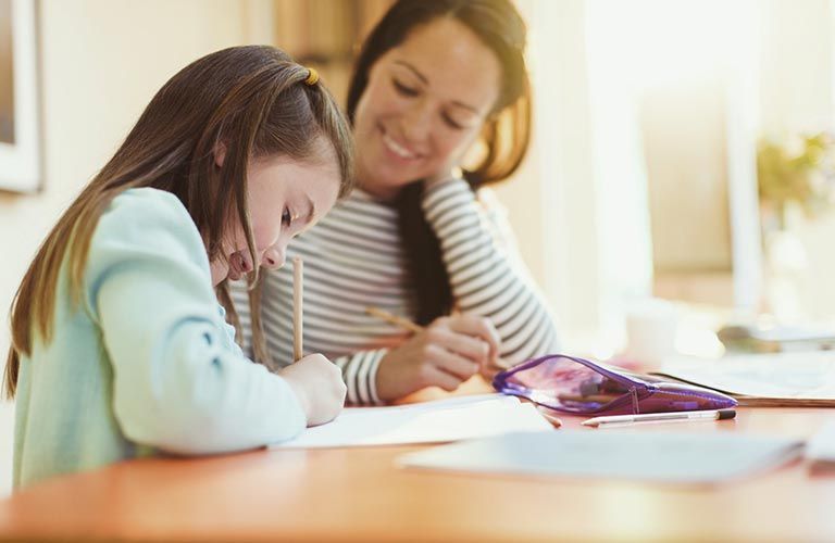 Femme avec sa petite fille en train de faire les devoirs
