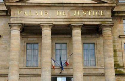 Façade du Palais de Justice, avec ses colonnes de pierre et des drapeaux français au-dessus de l’entrée