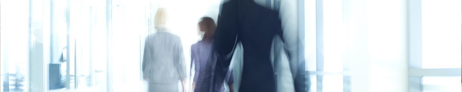 Des personnes floues marchant dans un couloir de bureau lumineux et blanc