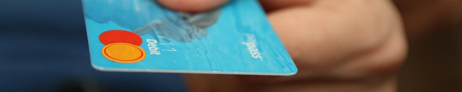 Gros plan sur une main tenant une carte de crédit bleue avec le logo Mastercard