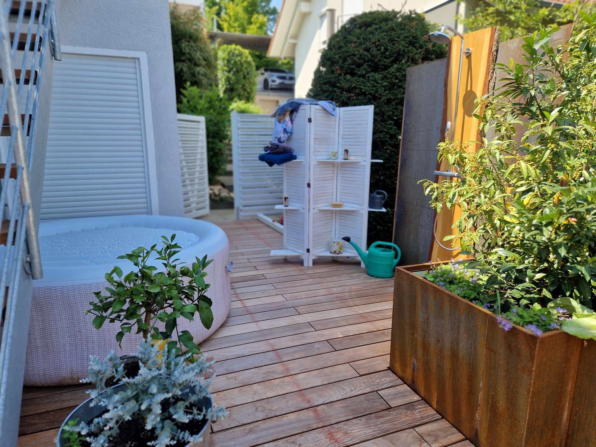 Hinterhof mit Whirlpool, Holzterrasse, Sichtschutz und Pflanzen.