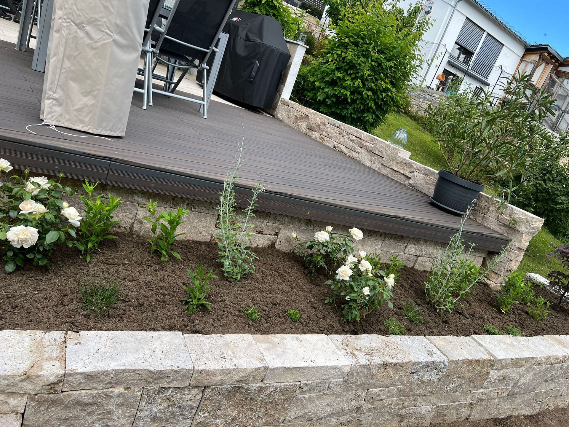 Eine Terrasse mit Tisch und Stühlen und Blumen in einem Garten.