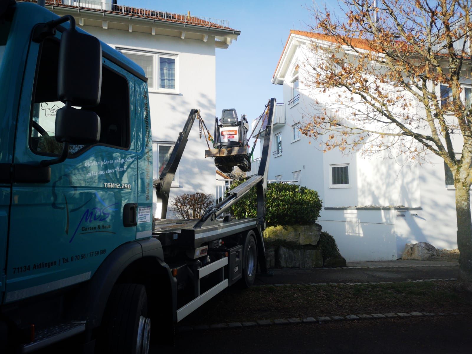 Ein blauer LKW steht vor einem weißen Haus