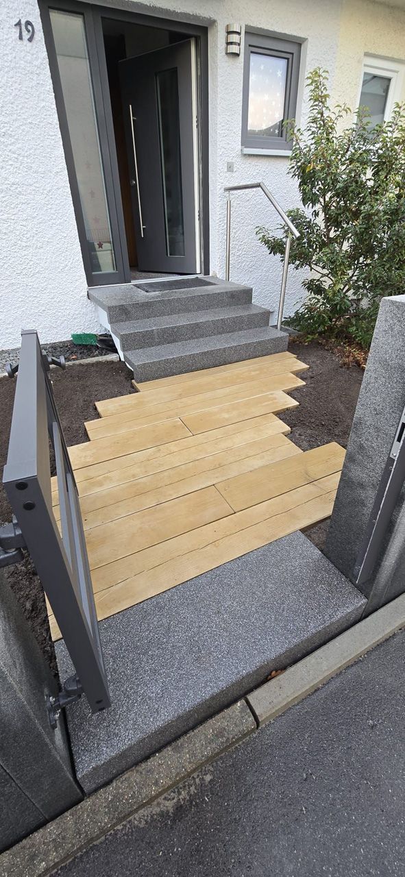 Vor einem Haus wird eine Holztreppe gebaut.