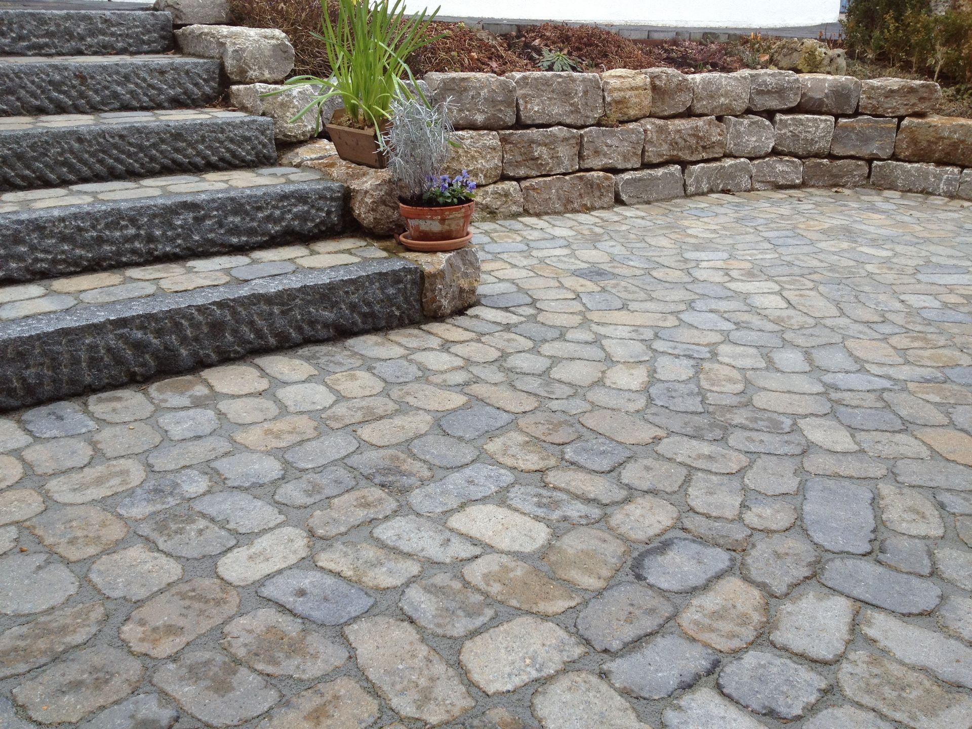 Steinterrasse mit Stufen und Stützmauer, Topfpflanzen.