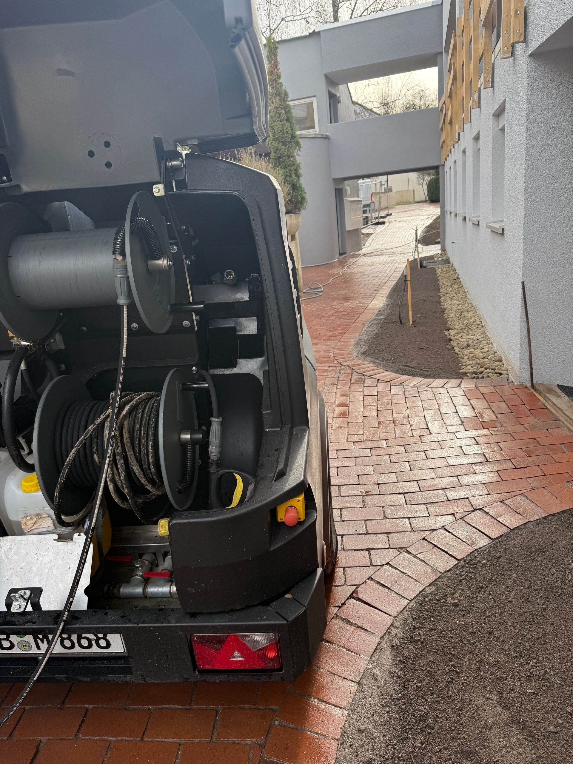 Ein schwarzer Lieferwagen parkt auf einem gepflasterten Gehweg neben einem Gebäude.