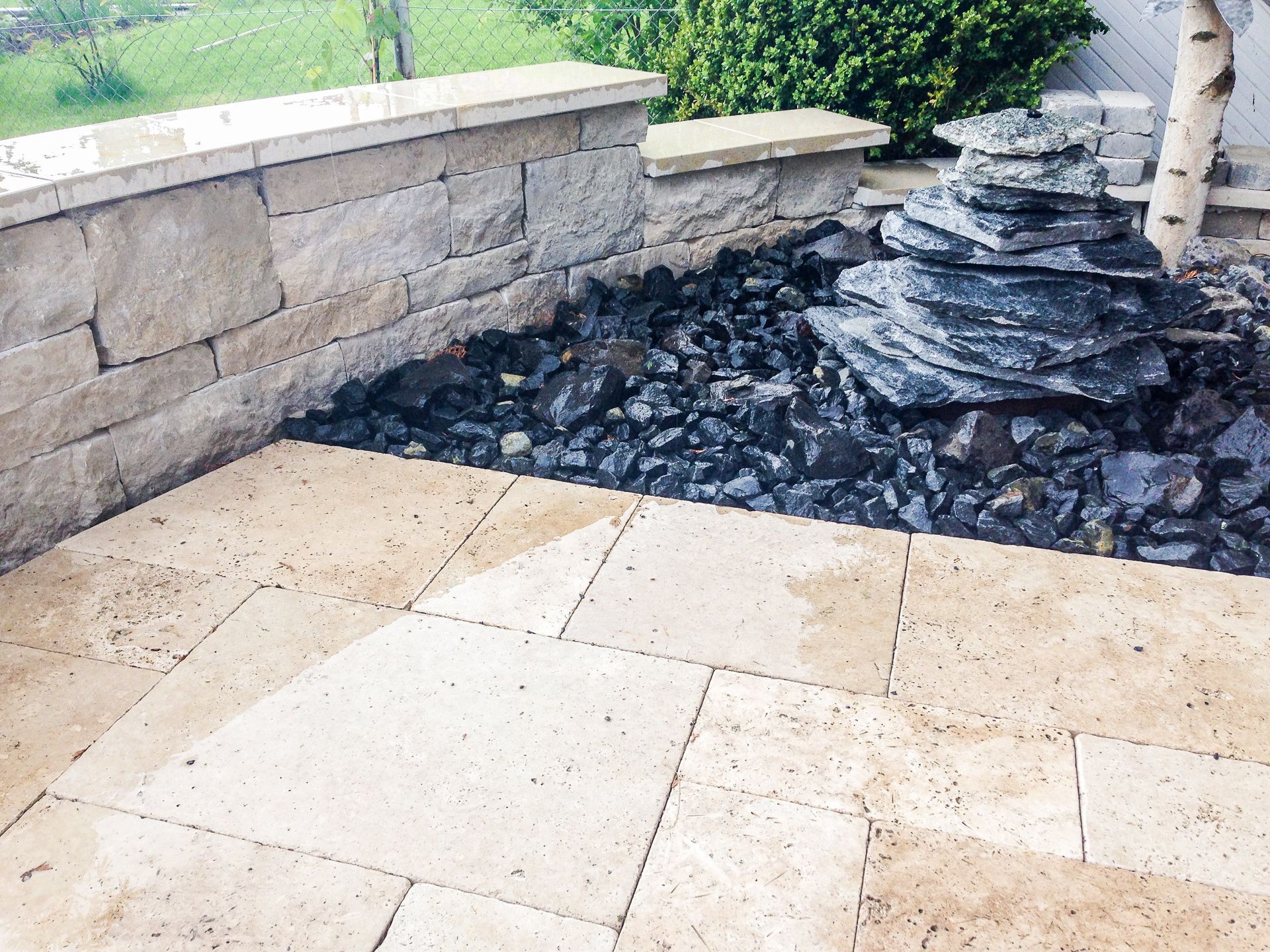 Eine Terrasse mit einer Steinmauer und einem Wasserfall im Hintergrund