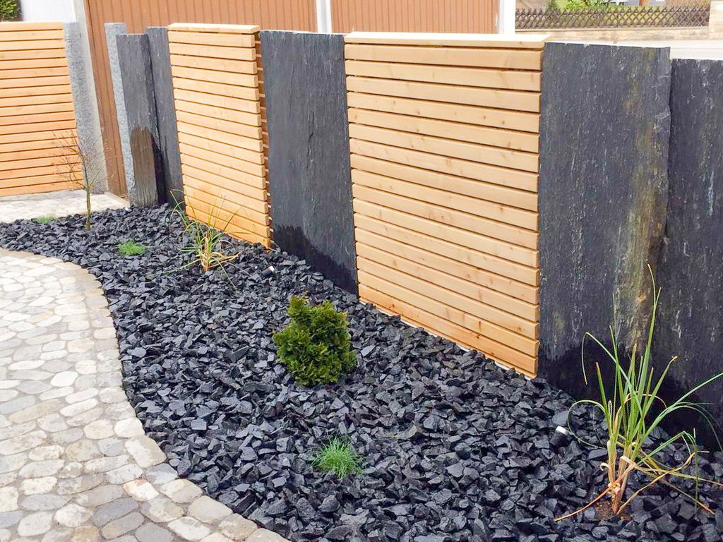 Ein Garten mit schwarzem Kies und einem Holzzaun